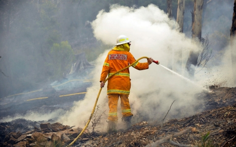 A New South Wales Rural Fire Service volunteer puts out a spot fire in the town of Bell, Australia.