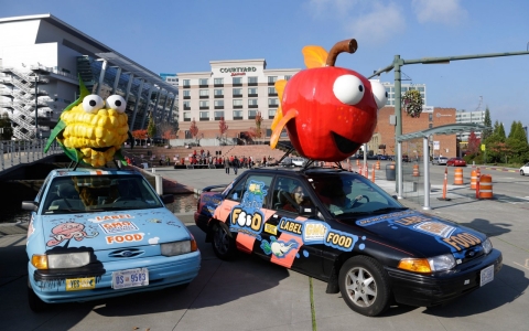 Cindy Black, right, and Jill Hill on Oct. 17, park a car in Tacoma, Wash., with a giant apple on top that promotes a "yes" vote on I-522 in Washington state.