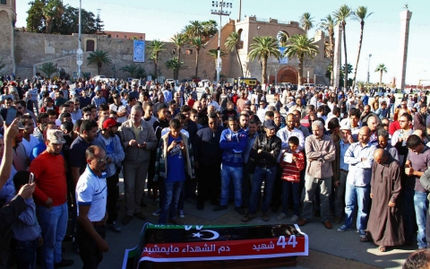 People assist a man who was injured Friday after Libyan militiamen opened fire on a crowd that wanted them to move out of the capital, Tripoli.