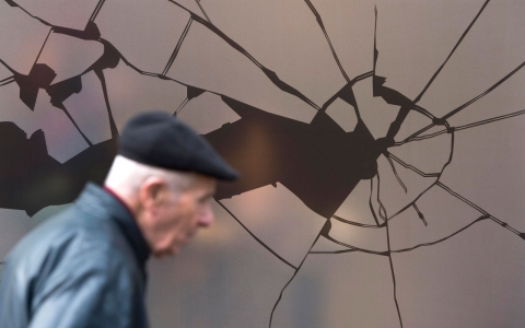 A man walks past a shop window decorated with a sticker simulating broken glass ahead of the 75th anniversary of the Kristallnacht pogrom