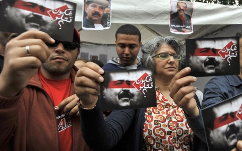 Besma Khalfaoui Belaid (center), holds up the images of her assassinated husband Chokri Belaid during a May Day rally in the capital Tunis