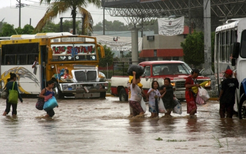 People carry their belongings as they evacuate from a flooded neighborhood in Acapulco on Sunday. 