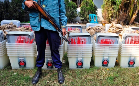 A member of the police stands guard in front of ballot boxes at a distribution center ahead of parliamentary elections in Dhaka on Saturday.